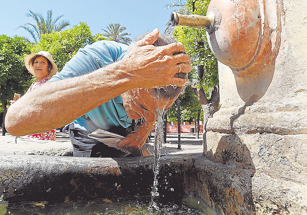 Un hombre se refresca en una fuente de Córdoba