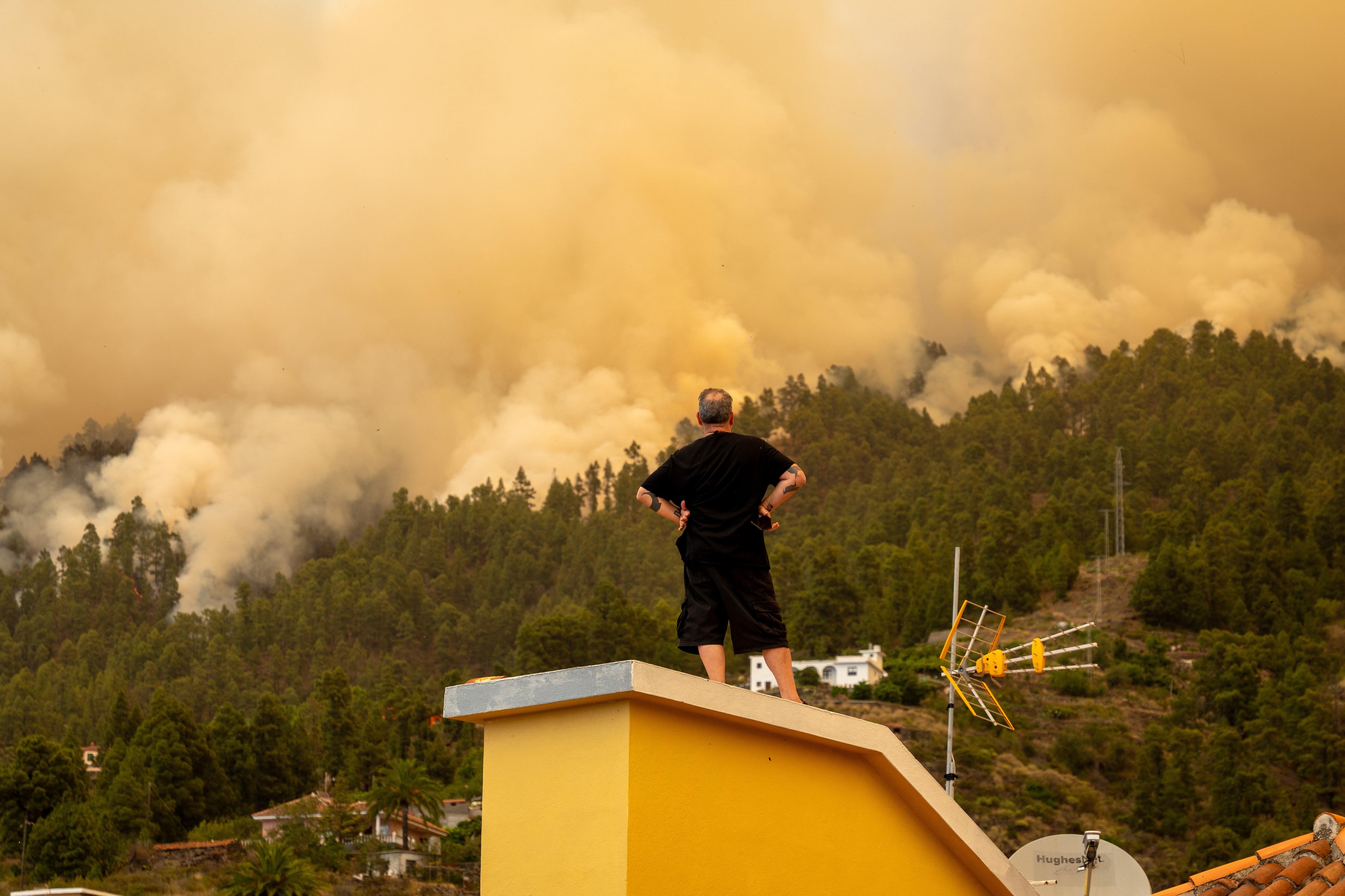 Un vecino observando desde su tejado el incendio declarado en Puntagorda, La Palma