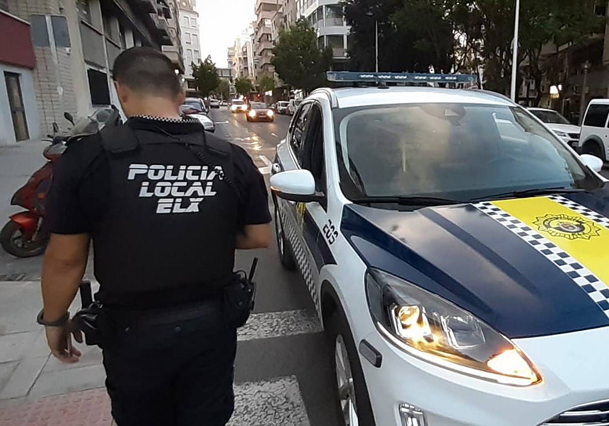 Imagen de archivo de un policía local de Elche junto a un coche patrulla