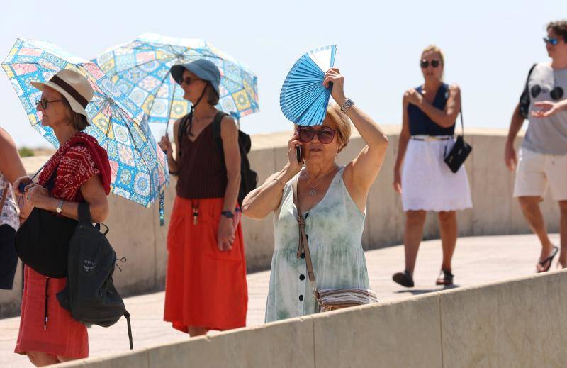 Una mujer se protege del sol con un abanico en el Puente Romano de Córdoba