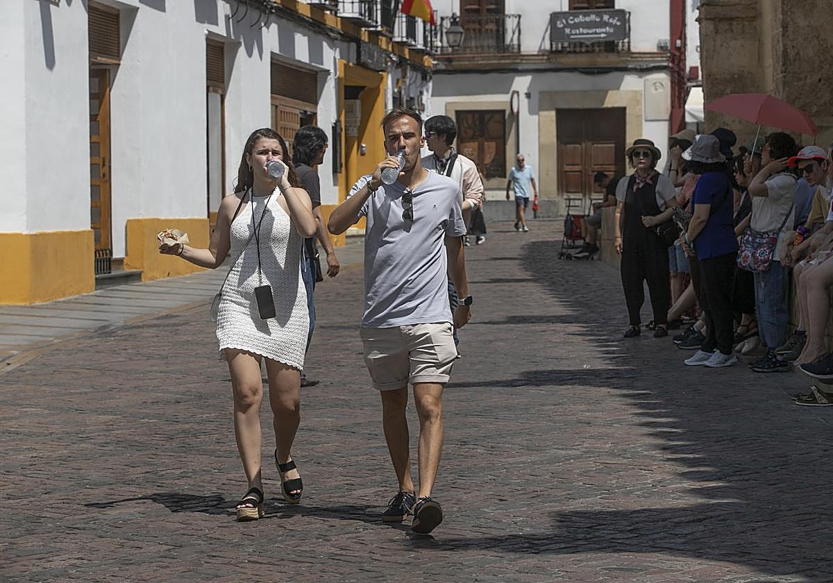 Dos turistas combaten el intenso calor mientras pasean por el entorno de la Mezquita-Catedral