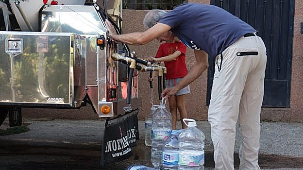 Un hombre llena una garrafa durante el primer reparto de agua de Emacsa en Las Jaras