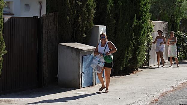 Una mujer llega con un par de garrafas al reparto de agua de Emacsa en Las Jaras