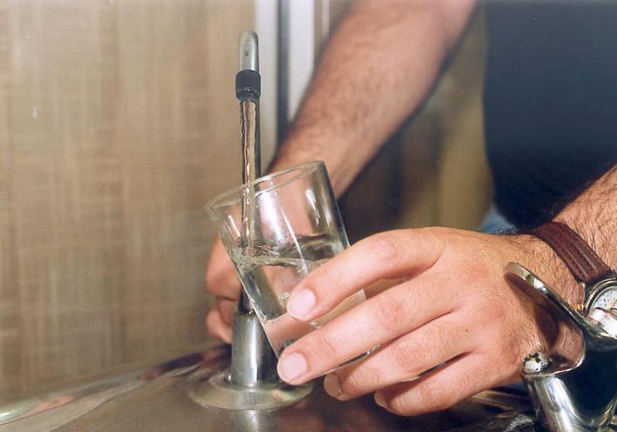 Una persona llena un vaso de agua del grifo