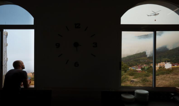 Un hombre observa desde una ventana de un restaurante de Aguamansa los trabajos de los helicópteros