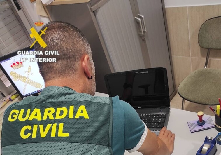 Imagen de un guardia civil con el portátil recuperado