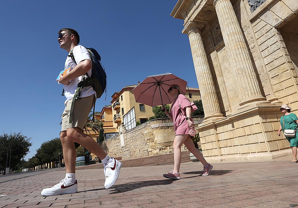 Una turista se protege del sol tras pasar por la Puerta del Puente