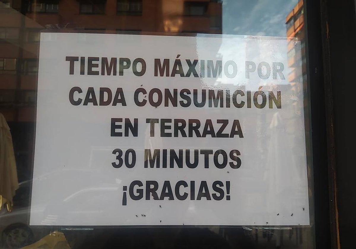 Cartel de un local de hostelería en el que se limita a media hora la consumición en la terraza