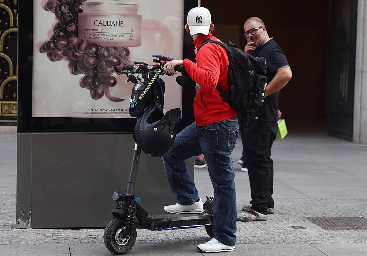 Un hombre charla con otro antes de retomar su ruta a bordo de un patinete