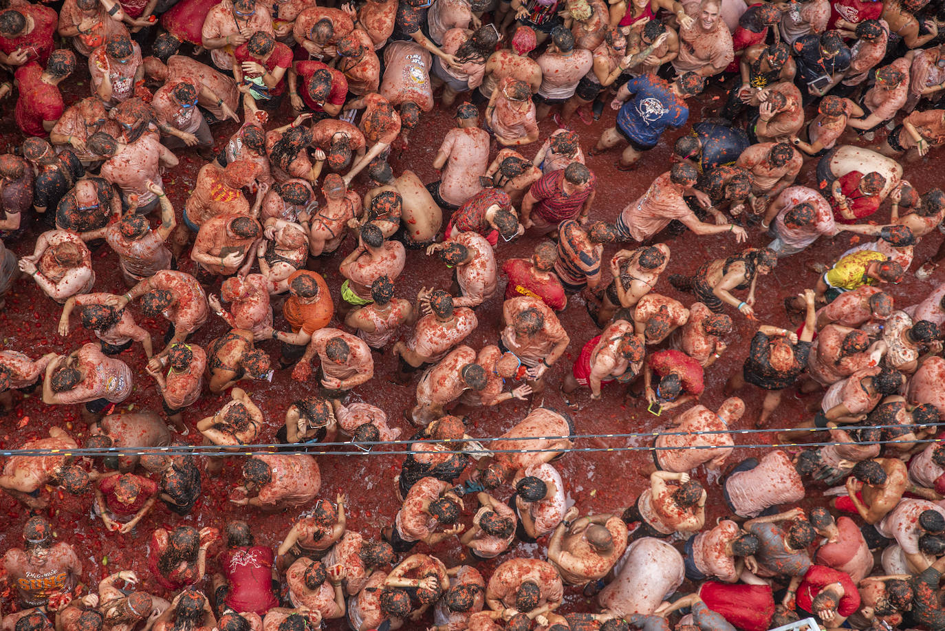 Centenares de personas completamente cubiertas de tomate durante la fiesta de La Tomatina, este 30 de agosto de 2023, en Buñol, Valencia