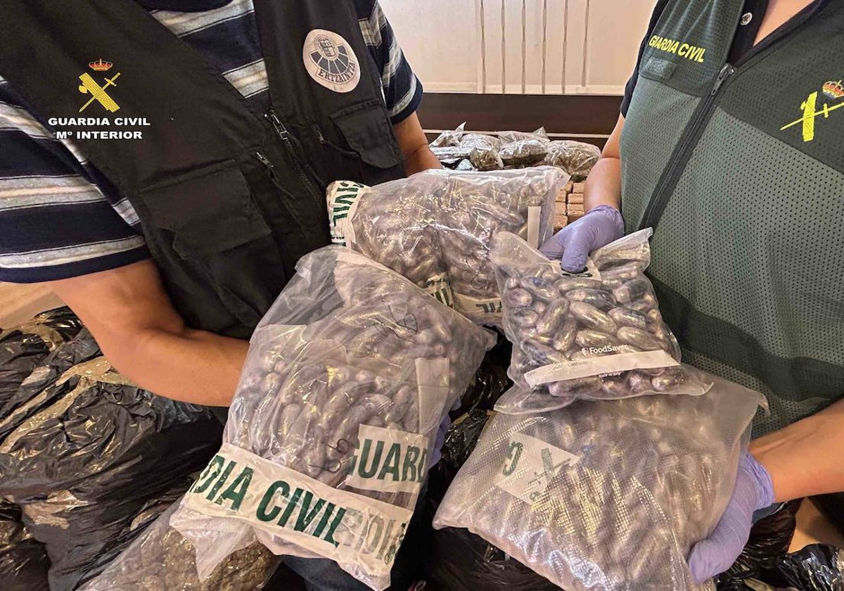 Una gente de la Ertzaintza y otro de la Guardia Civil muestran parte de la droga incautada