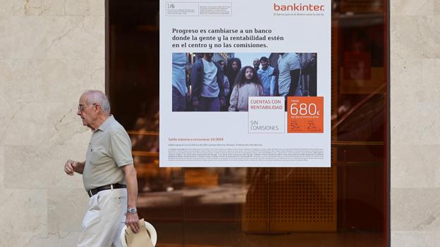 Un hombre pasa delante de un cartel publicitario de Bankinter en Córdoba