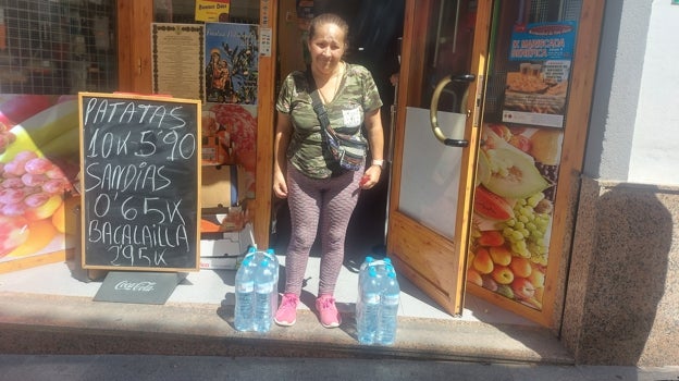 Una vecina con botellas de agua mineral a la salida de una tienda en Baena este domingo