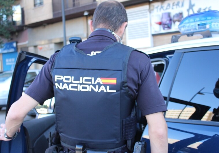 Un agente de la Policía Nacional sube a un coche patrulla.