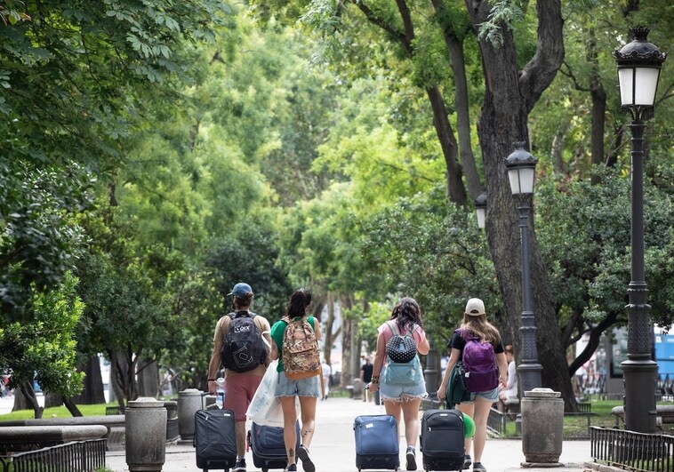 Un grupo de turistas cruza el Paseo del Prado, la arbolada del Paisaje de la Luz