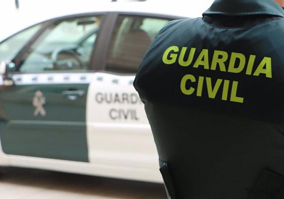 Imagen de archivo de un guardia civil junto a un coche patrulla