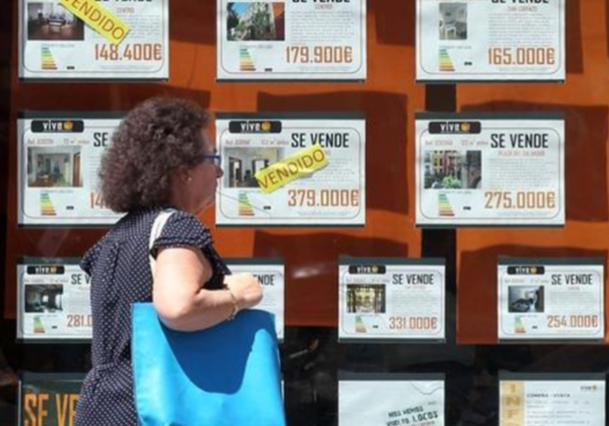 Una mujer pasea frente a una inmobiliaria con pisos en venta, en foto de archivo