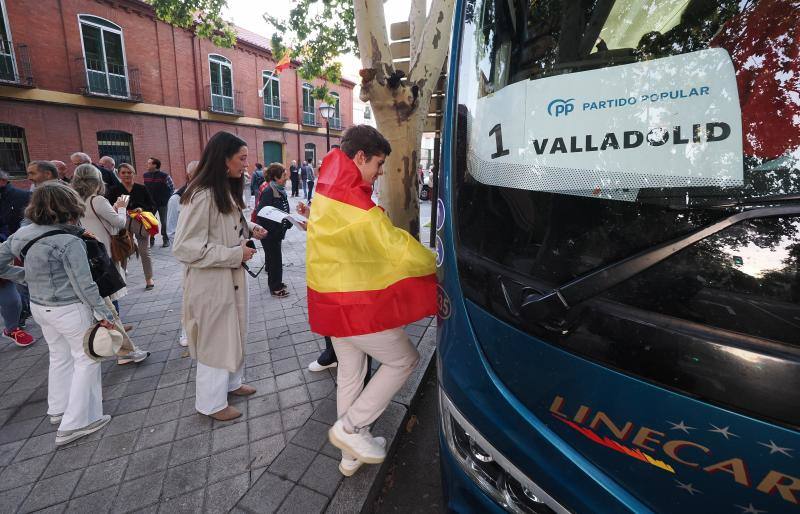 Uno de los asistentes a la concentración, ataviado con una bandera de España, subiendo al bus de Valladolid que le tenía que llevar a Madrid