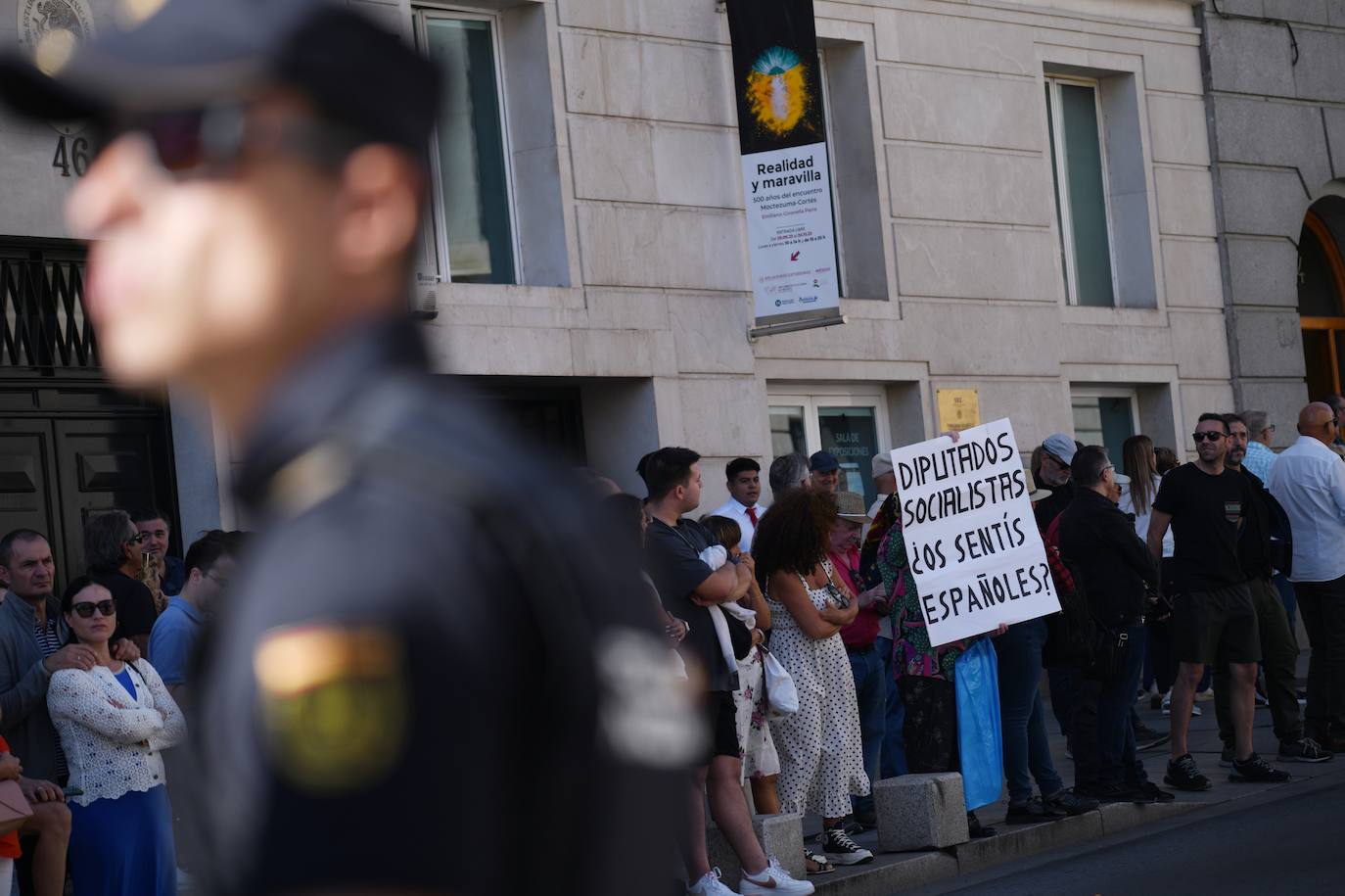 Un grupo de personas a las puertas de la primera sesión del debate de investidura del líder del PP, en el Congreso de los Diputados protestan contra los diputados del PSOE