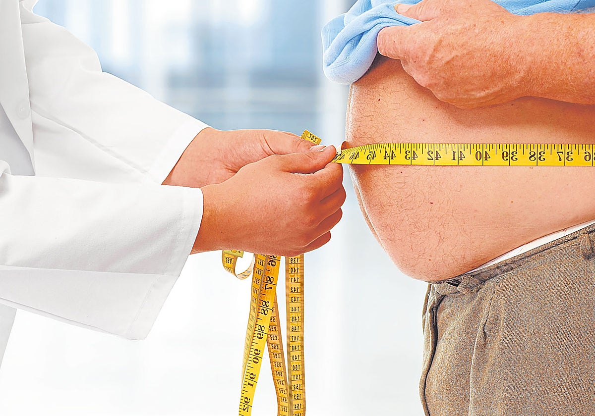Un sanitario mide el abdomen de un paciente con sobrepeso