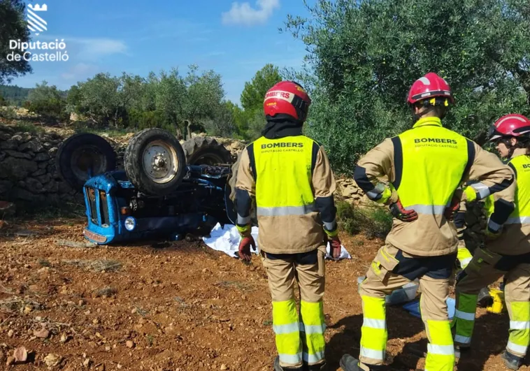 Bomberos junto al tractor volcado en el lugar donde murió el conductor.