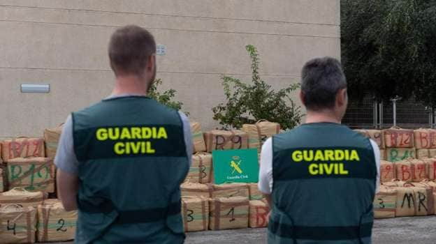 Dos agentes custodian los fardos de hachís intervenidos en la operación Rescatada, tras abortar una descarga de hachís en Sitges (Barcelona)