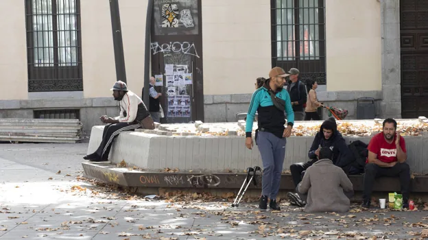 Varias personas, este lunes al mediodía, en los bancos de la plaza de Tirso de Molina