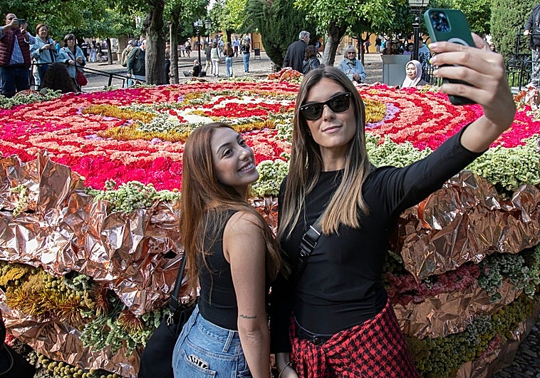 Dos jóvenes se fotografían, junto a la instalación que se montó en el Patio de los Naranjos