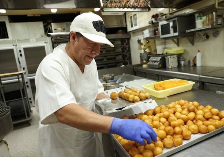 Un pastelero elabora buñuelos de viento, típicos de estas fechas, en una panadería madrileña