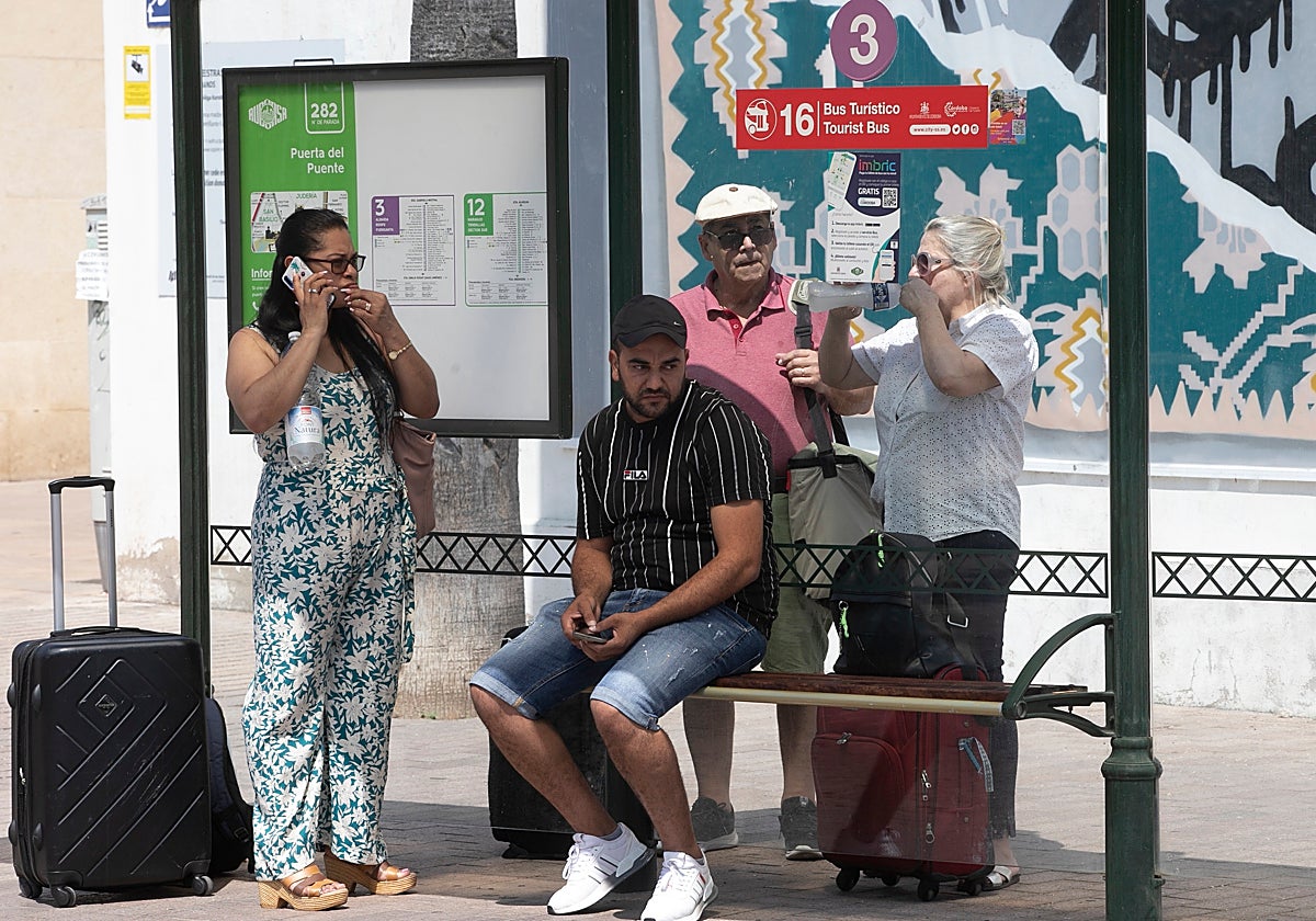 Dos jóvenes turistas esperan en una parada de Aucorsa en la Ribera este verano