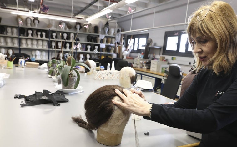 Imagen principal - Una empleada realiza, a mano y con pelo natural, una peluca para artistas en la planta donde se guarda todo el vestuario de las óperas