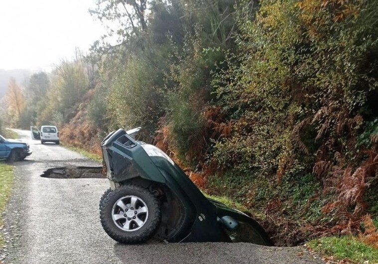 Uno de los autos dentro del socavón en la vía que une las localidades de La Faba y La Cernada en León