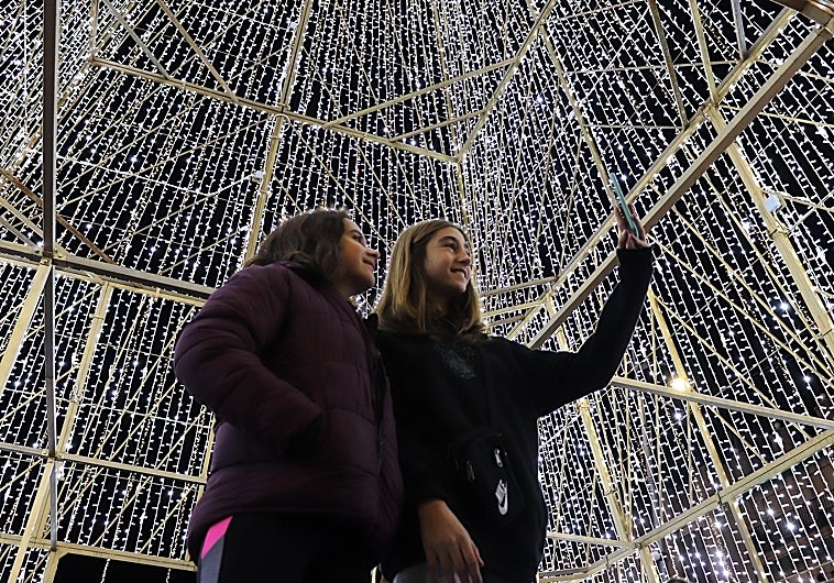 Dos jóvenes se fotografían bajo la iluminación navideña de Lucena en 2022