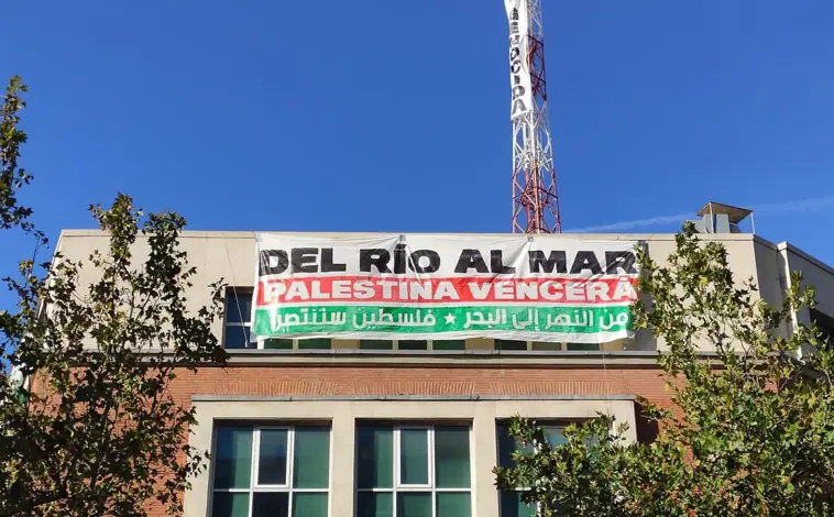 Imagen principal - Cuelgan una bandera de Palestina y una pancarta frente a la embajada de Israel en Madrid