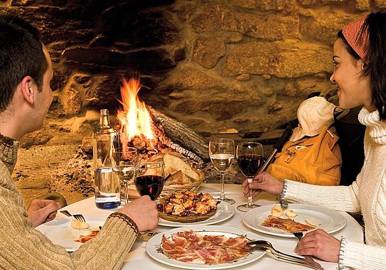 Una pareja disfrutando una cena al calor de la chimenea en una casa rural