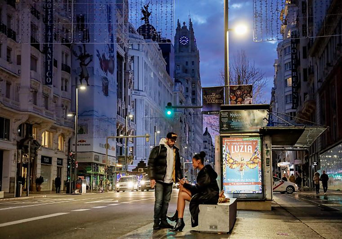 Dos pasajeros esperan transporte en el amanecer del primer día del 2023
