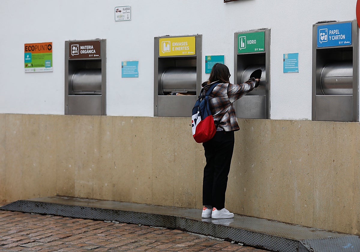 Una joven introduce residuos en un contenedor de vidrio