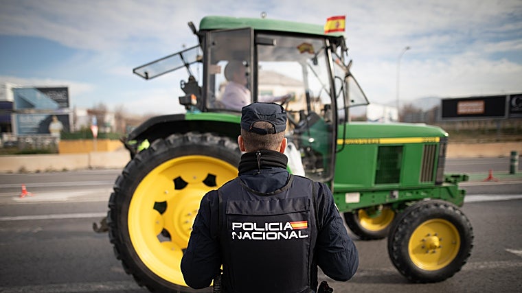 Un agente de la Policía Nacional observa el paso de uno de los vehículos participantes