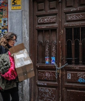 Imagen secundaria 2 - La Risueña, antaño un bar repleto de jóvenes, hoy cerrado y empapelado; en las fotos inferiores, otro local disponible para venta o alquiler en la Carrera de San Jerónimo, y una mujer pasa por delante de una espacio en desuso