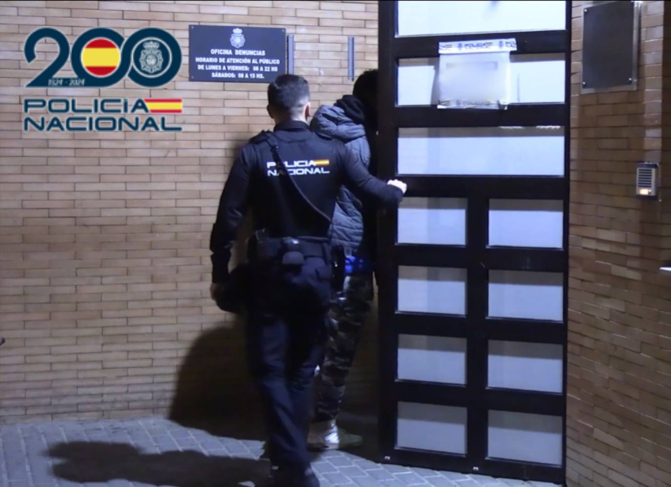 Imagen de un agente introduciendo a uno de los detenidos a comisaría