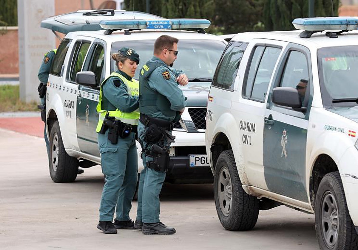 Una patrulla de la Guardia Civil prepara su equipo al lado de dos vehículos