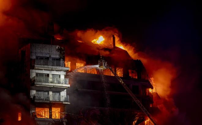 El edificio en llamas y los bomberos trabajando