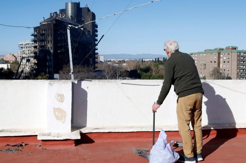 Un vecino barre las cenizas que han quedado en su terraza tras el incendio del edificio