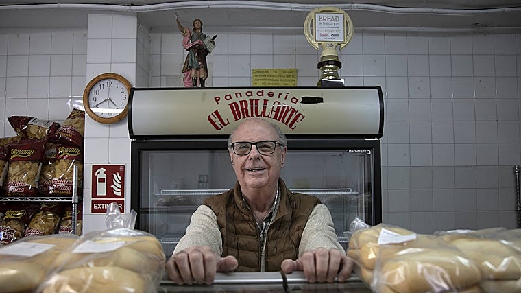 Juan Palma sonríe tras el mostrador y tras él se ve el premio de José Roldán