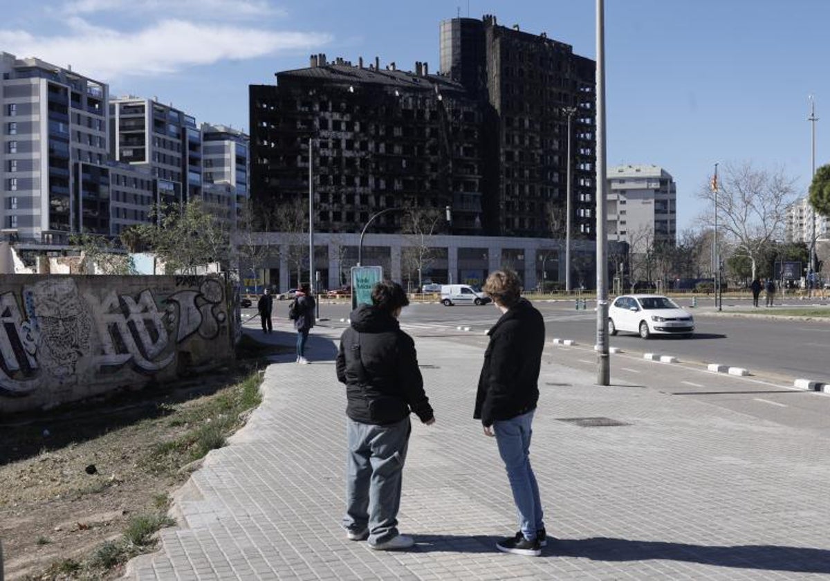 Unas personas observan el exterior del edificio que sufrió un incendio en el barrio de Campanar de Valencia