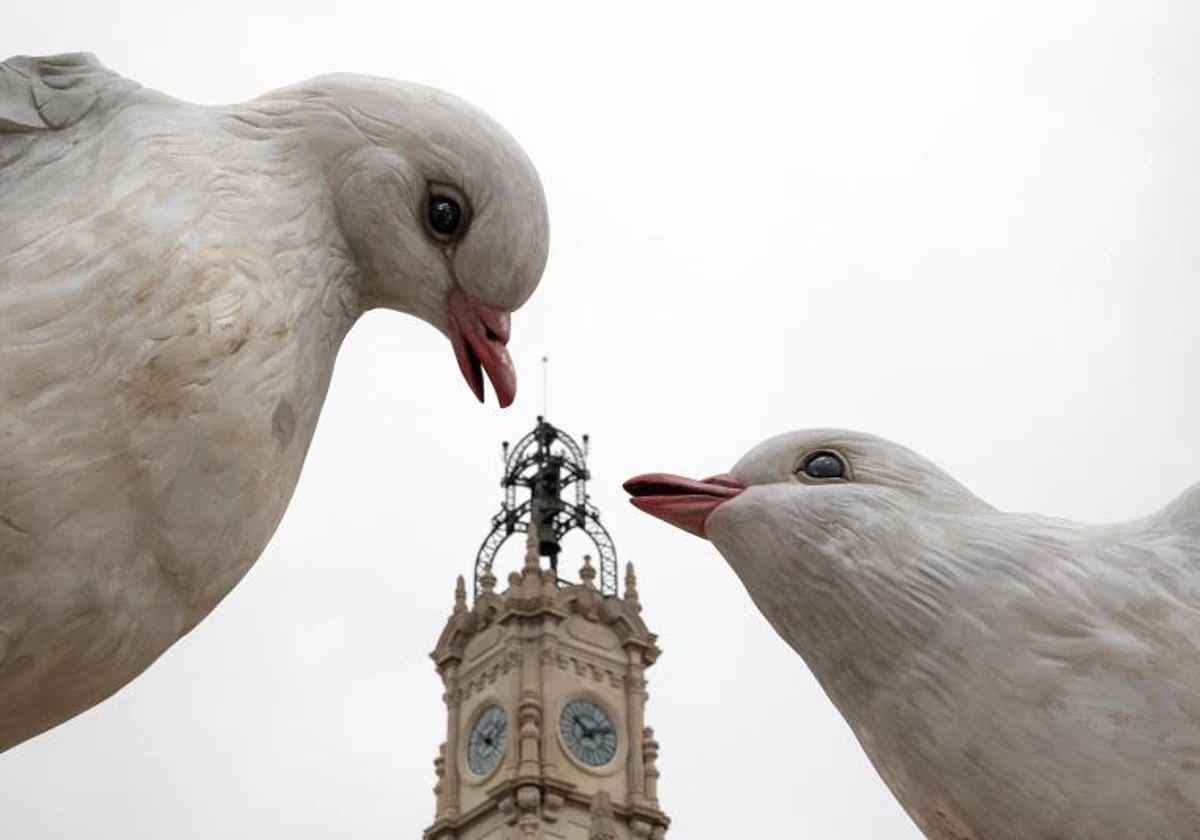 Vista del reloj del Ayuntamiento de Valencia entre dos palomas que forman parte de la falla municipal