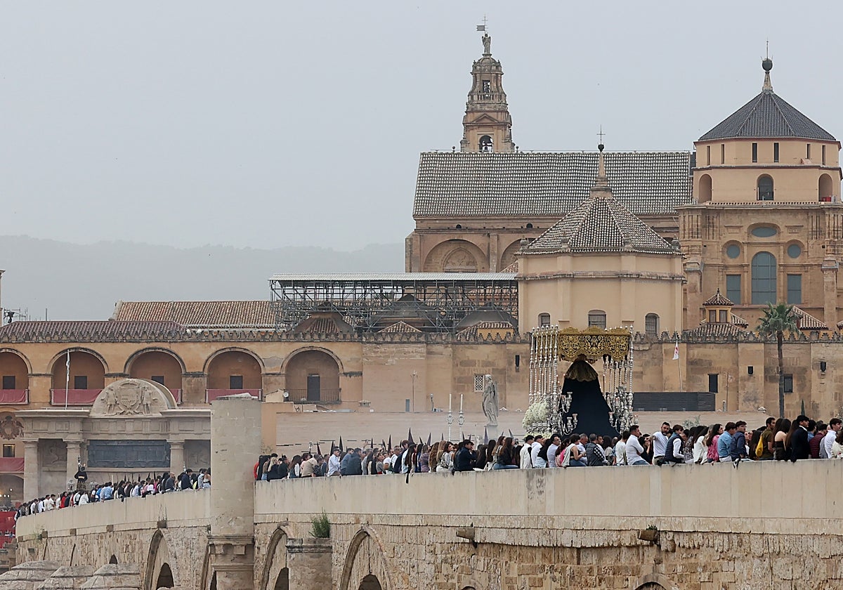 La hermandad de la Vera-Cruz cruza el Puente Romano con el cileo cubierto