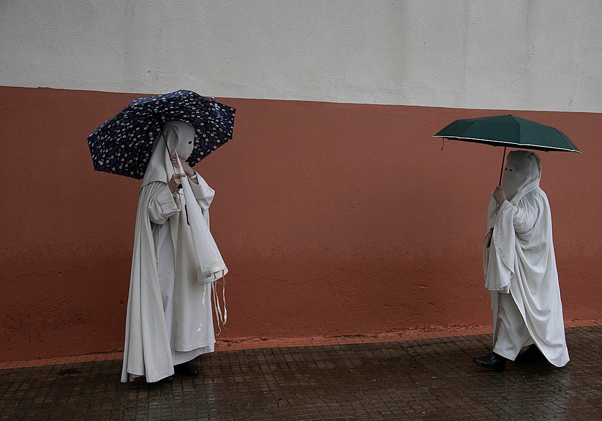 Dos nazarenos de la Merced bajo paraguas este Lunes Santo