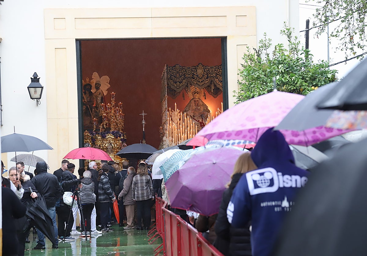 Fila de hermanos y devotos ante las puertas de la iglesia con las imágenes de la Merced