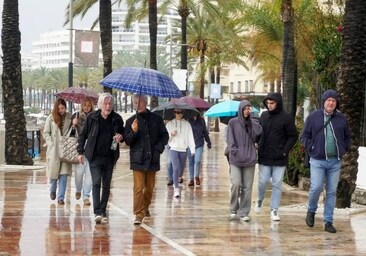 Turistas con paraguas en el paseo marítimo de Marbella